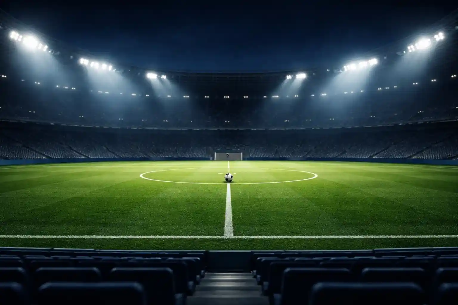 Estadio de fútbol iluminado de noche con campo de césped natural visto desde la grada